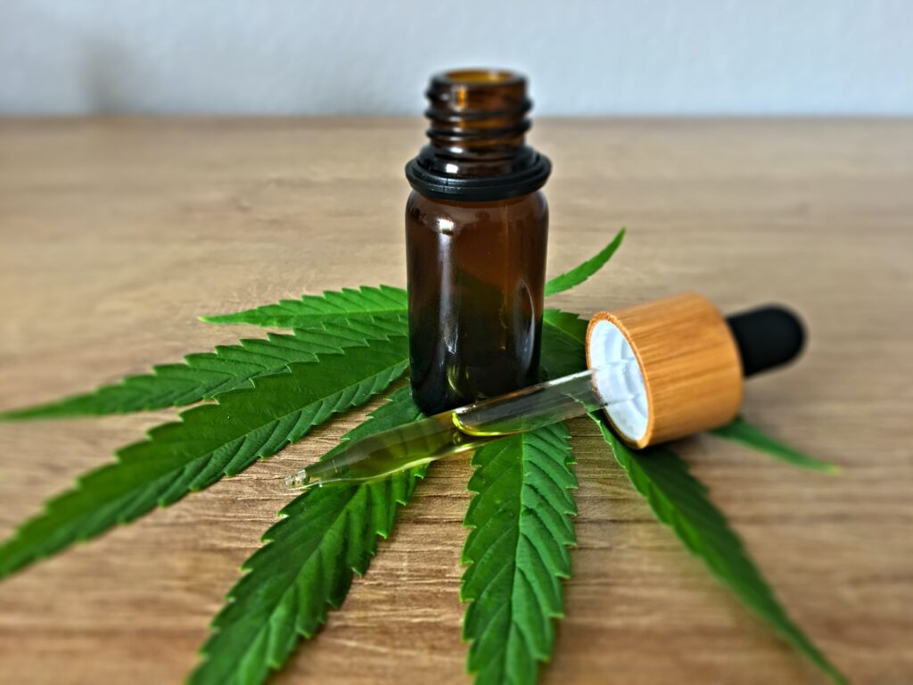 cbd oil in a dropper bottle with a cannabis leaf under it