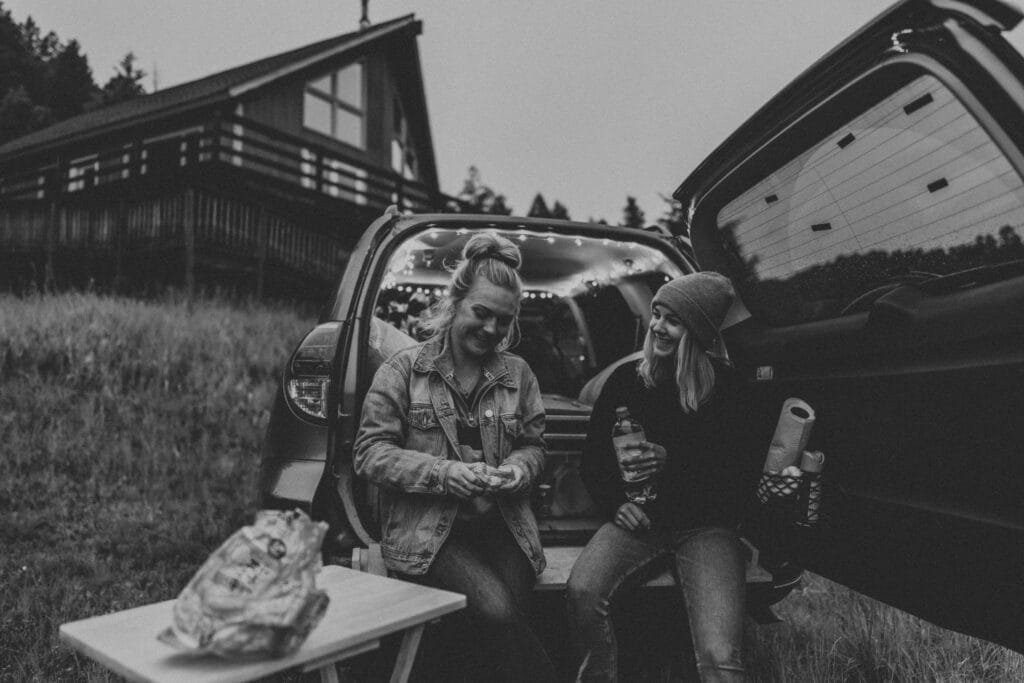 two women siting on back of car on the cannabis friendly road trip