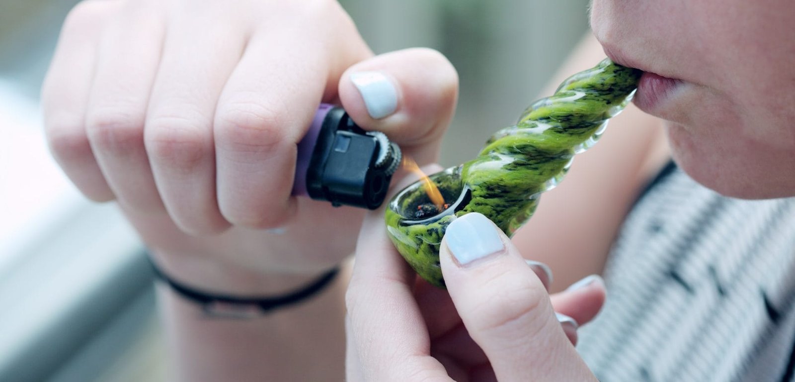 person lighting a pipe of cannabis